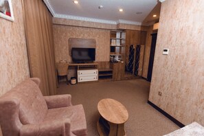 A living room with a television, a sofa, a coffee table, and a cabinet. - Baku Hotel Ganja (Ganja)