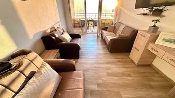 Una sala de estar moderna con sofá, mesa de centro, televisión y balcón con vistas.