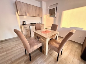 Une cuisine moderne avec des meubles en bois, une table à manger avec des chaises et une petite fenêtre.