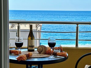 A table with a bottle of wine, two glasses, and a snail on a balcony overlooking the sea. - Saray Hotel (Bar)