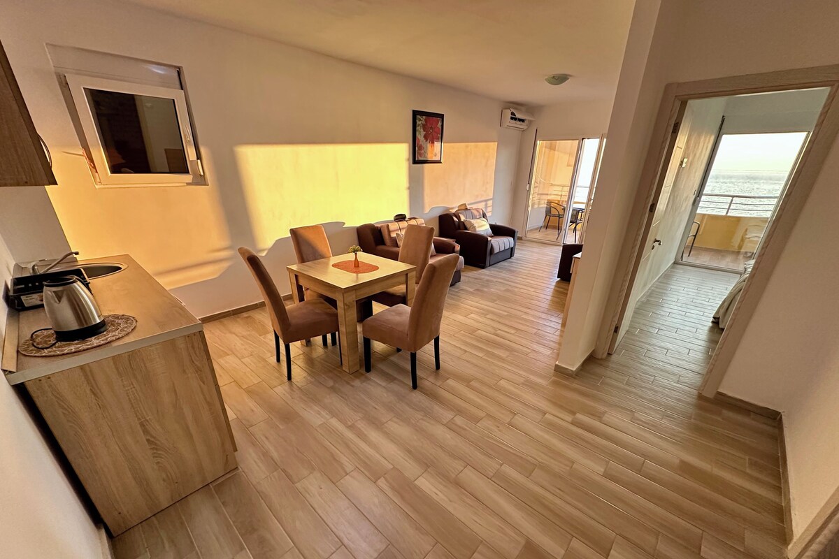 A modern apartment with a dining area, kitchen, and a balcony with a view.