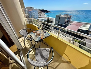 A balcony with a table and chairs, overlooking a beach and buildings. - Saray Hotel (Bar)