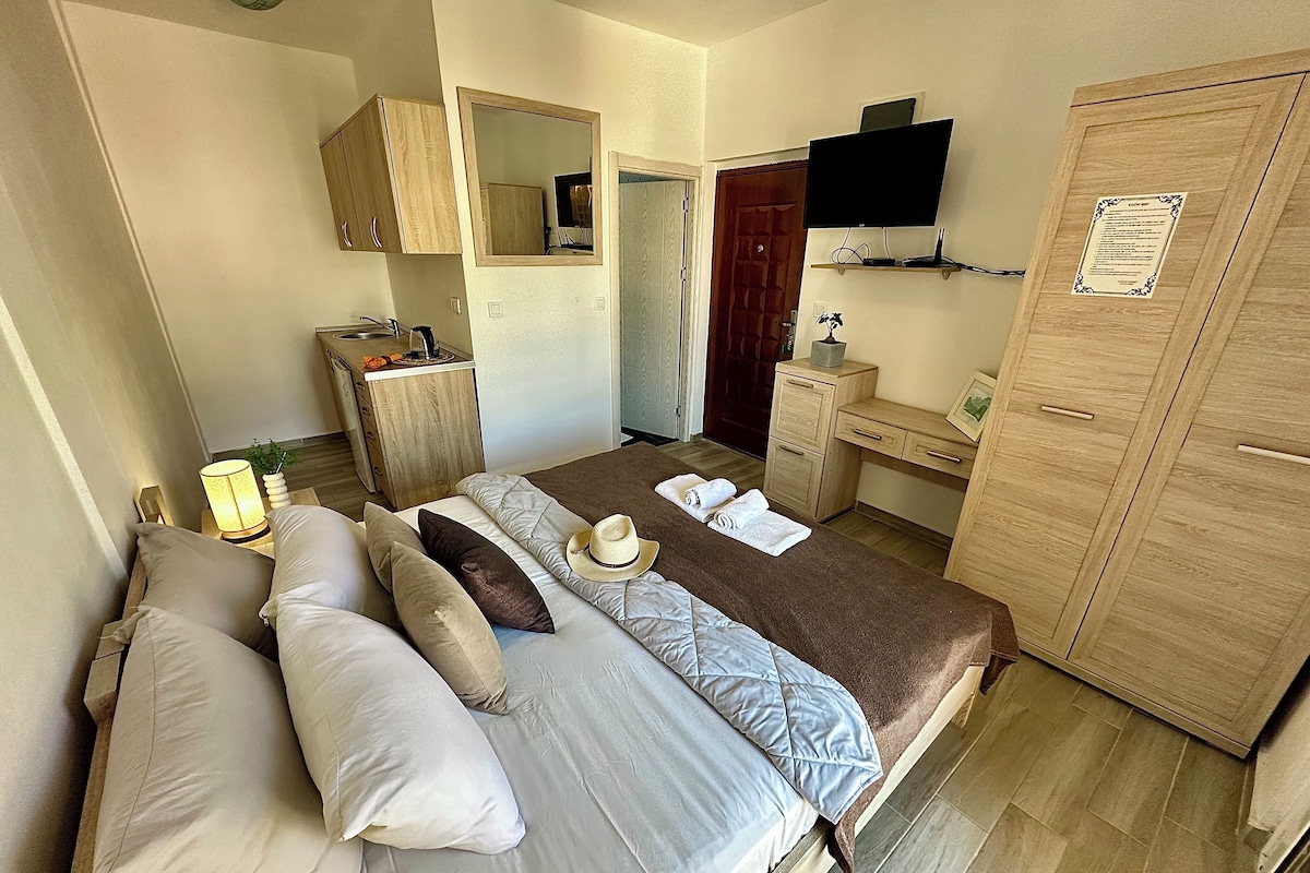 A bedroom with a bed, bedside tables, a wardrobe, a desk, a mirror, and a television.