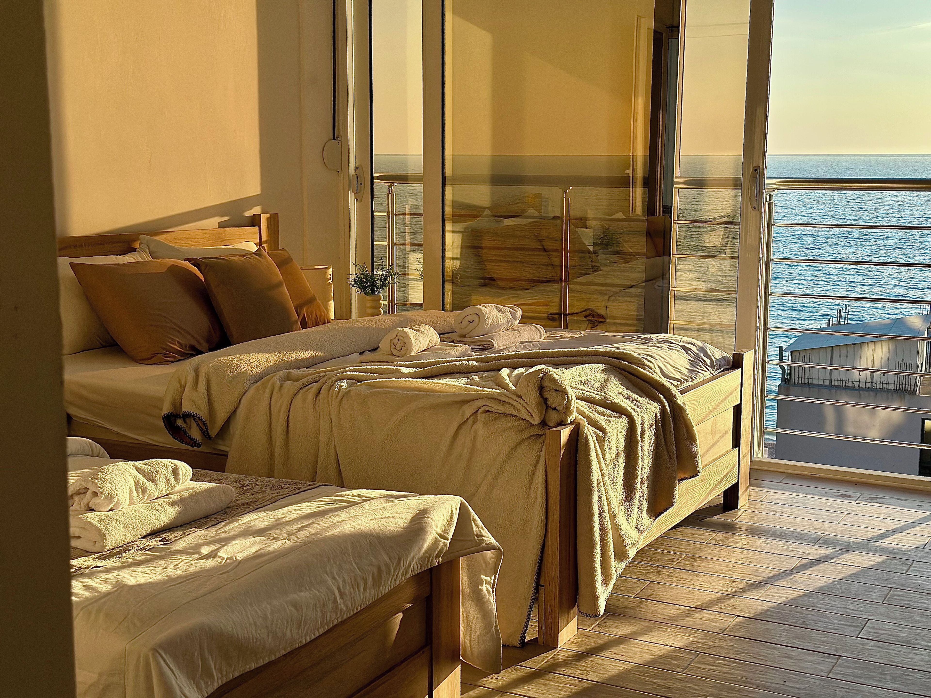 Un dormitorio con una cama grande, una cama más pequeña y un balcón con vista al mar.