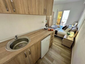A compact kitchen with a sink, dishwasher, and wooden cabinets. - Saray Hotel (Bar)