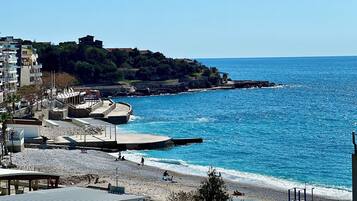 A coastal area with a beach, promenade, and buildings.