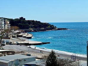 A coastal area with a beach, promenade, and buildings. - Saray Hotel (Bar)