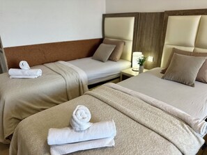 Two twin beds with headboards, a nightstand with a lamp, and a rolled towel on the floor. - Saray Hotel (Bar)