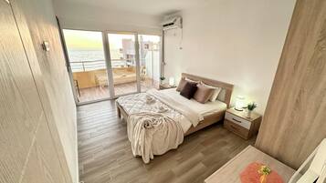 A bedroom with a bed, bedside table, and a view of the sea through a sliding door.