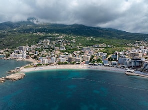 A coastal town with buildings along the shore and a mountainous backdrop. - Saray Hotel (Bar)