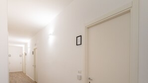 A hallway with wooden flooring, white walls, and closed doors. - Casa Stazione (Verona)
