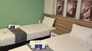 A hotel room with two single beds, a wooden headboard, a green wall, and three framed artwork pieces. - M3 Studio Hotel by Concavus (Camacari)