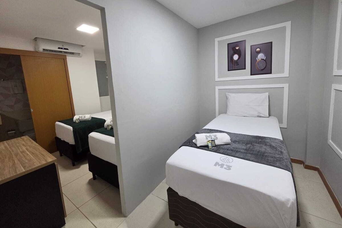Habitación de hotel con cama, escritorio, silla, espejo y aire acondicionado instalado en la pared.