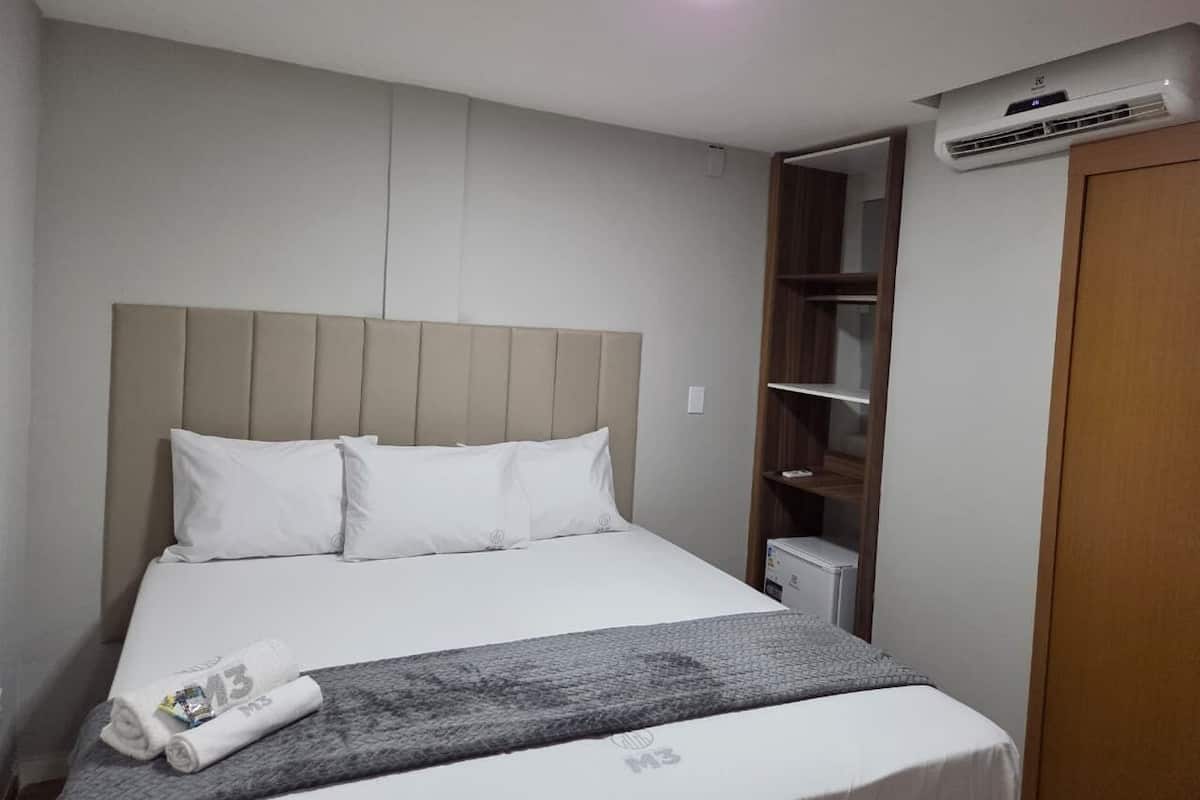 Una habitación de hotel con una cama, un armario y un equipo de aire acondicionado.