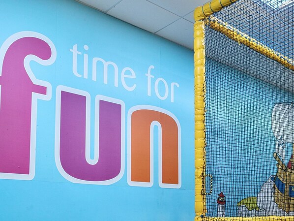 A wall with the text 'time for fun' and a netted play area.