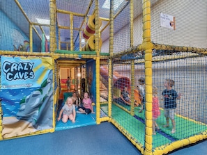 Un espace de jeux intérieur doté d’une enceinte en filet, d’un toboggan et d’une zone de jeux appelée « Grottes folles ».