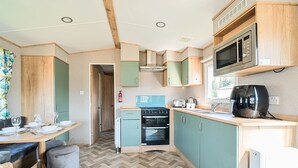 A compact kitchen with a herringbone floor, a microwave, a stove, and a toaster. - Dune Delight - Hayling Island (Hayling Island)