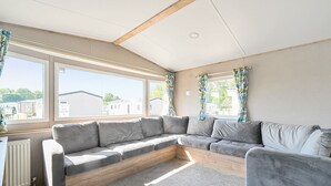 A modern living room with a sectional sofa, large windows, and a wooden ceiling. - Dune Delight - Hayling Island (Hayling Island)