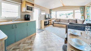 Ein kompaktes Wohnmobil-Interieur mit Küchenzeile, Sitzgelegenheit und großen Fenstern.