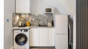 Une cuisine compacte équipée d’un lave-linge, d’un four à micro-ondes et d’un réfrigérateur.
