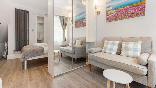 Une chambre moderne avec un lit, un canapé, une petite table et un grand miroir.
