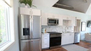Een moderne keuken met roestvrijstalen apparatuur, witte keukenkastjes en een marmeren achterwand.
