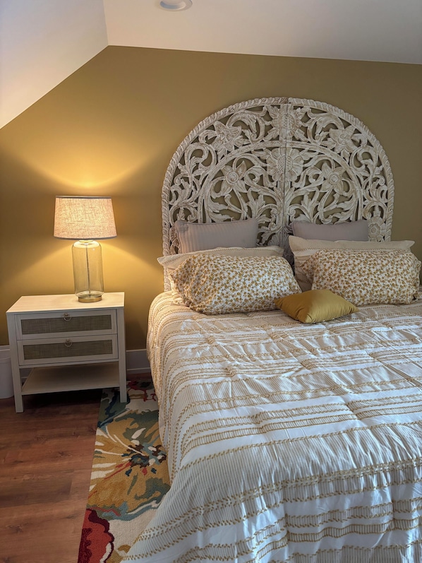Une chambre à coucher comprenant un lit, une table de chevet, une lampe et une tête de lit décorative.