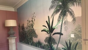 A bedroom with a large tropical mural on the wall, a bed, and a lamp. - Your cosy, quiet suite in the heart of Carcassonne! (Carcassonne)