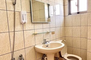 Un baño con lavamanos, inodoro y cabezal de ducha de mano.