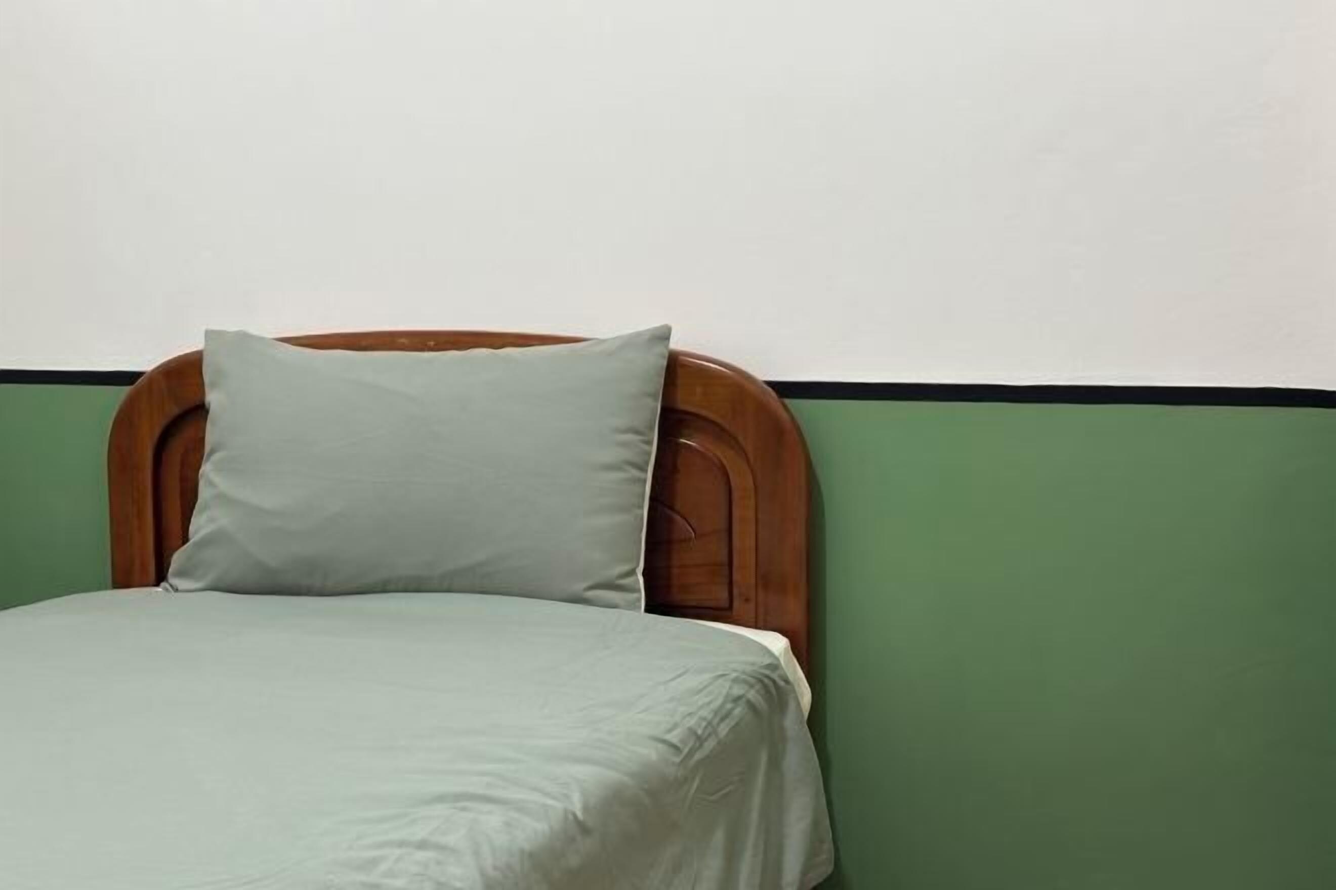 A bed with a wooden headboard and a green wall.