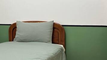 A bed with a wooden headboard and a green wall.