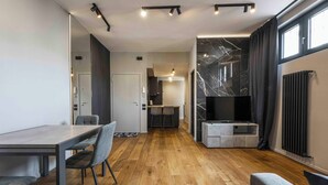 A modern living room with a wooden floor, a dining area with a table and chairs, a TV, and a fireplace. - Gozzoli by MMega (Florence)