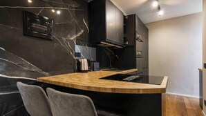 A modern kitchen with a marble backsplash, wooden countertop, and two grey chairs. - Gozzoli by MMega (Florence)