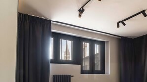 A room with a window, black curtains, a radiator, and a ceiling light fixture. - Gozzoli by MMega (Florence)