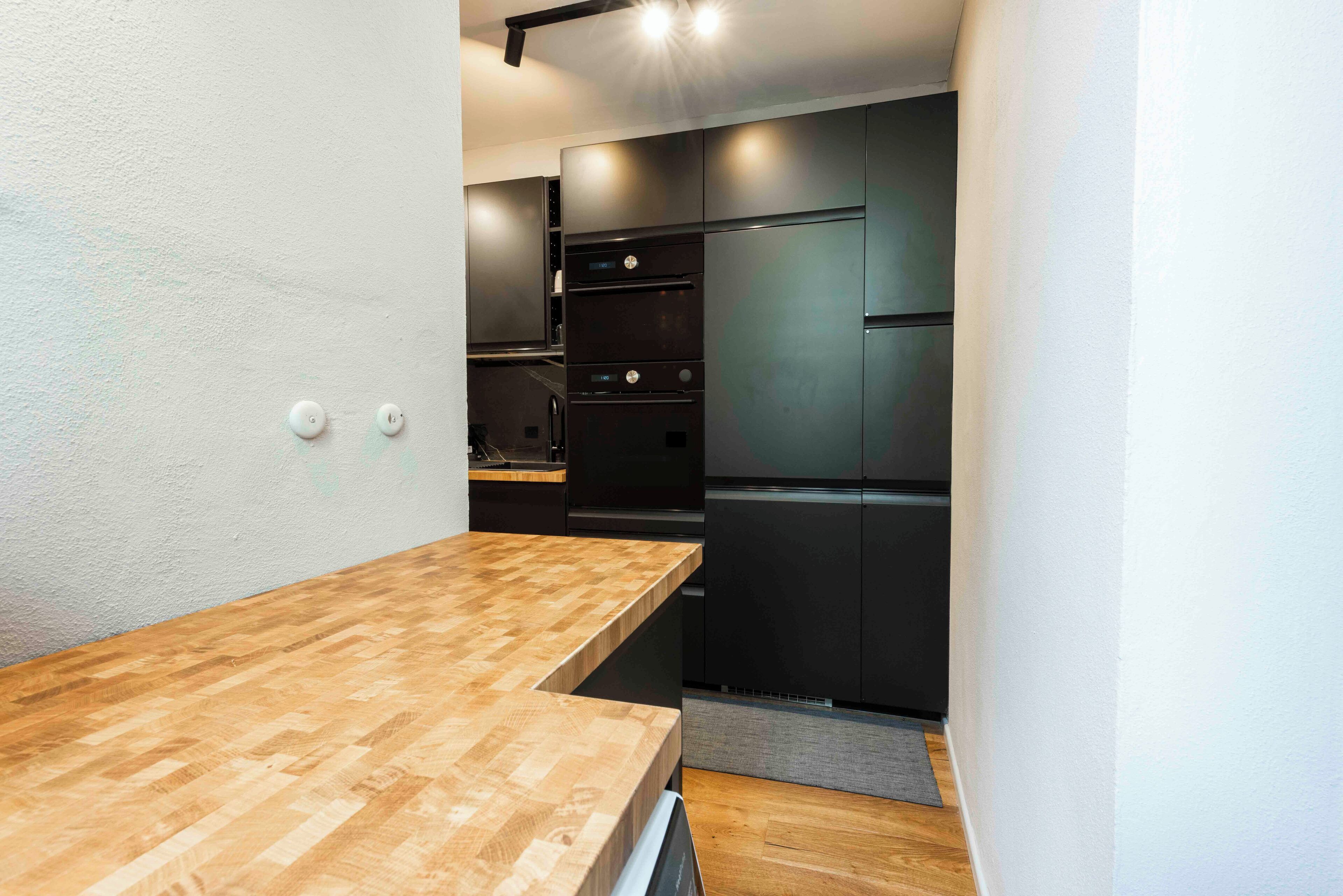A compact kitchen with a wooden countertop, black appliances, and white walls.