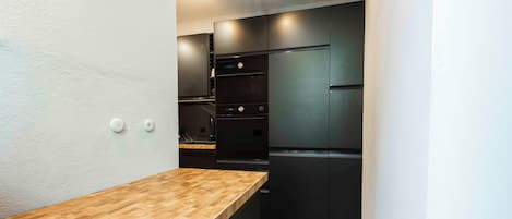 A compact kitchen with a wooden countertop, black appliances, and white walls.