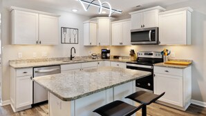 A modern kitchen with white cabinetry, granite countertops, and stainless steel appliances. - Contemporary and Relaxing Getaway - 10 minute walk to the beach (Oak Island)