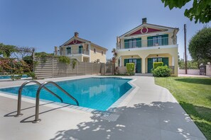 A swimming pool with metal railings, a two-story house with a balcony, and a well-maintained lawn. - Villa 'Anogia  1' with Mountain View, Wi-Fi and Air Conditioning (Laganas)