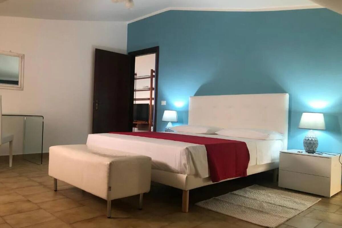 A bedroom with a bed, bedside tables, a chair, and a desk.