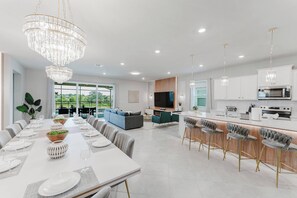 Una cocina moderna con una isla central, electrodomésticos integrados e iluminación colgante.