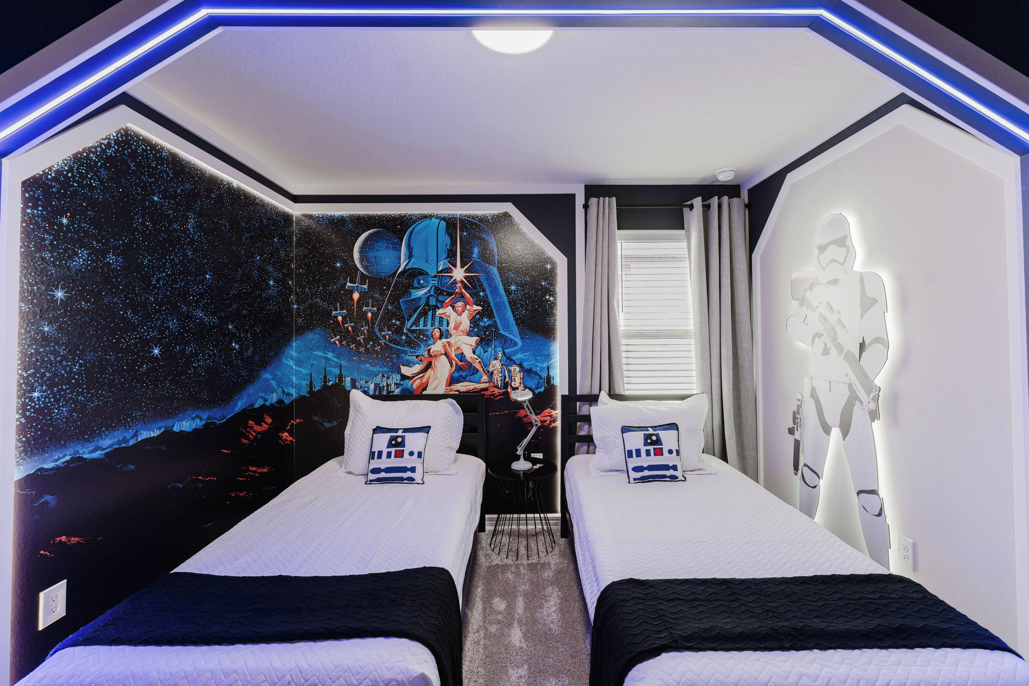A room with two beds, a mural of a space scene, and a Star Wars-themed wall decoration.