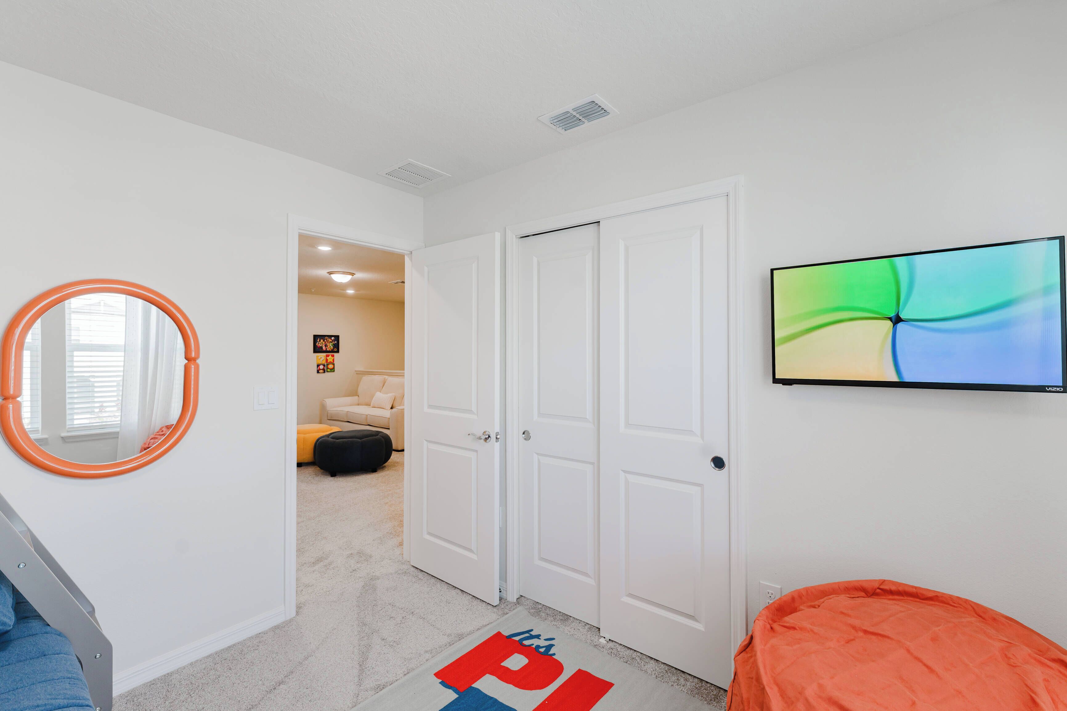 A bedroom with a bed, a TV, a door, and a mirror.