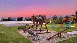 A playground with a swing set, slide, and seesaw.