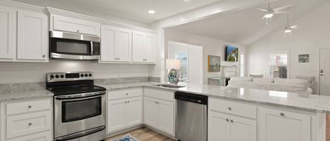 A modern kitchen with white cabinetry, stainless steel appliances, and a blue patterned rug.