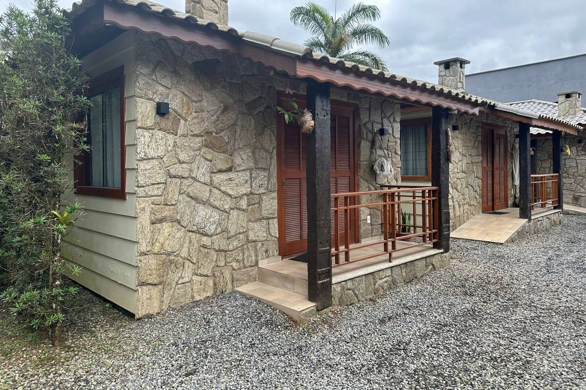 Una casa de piedra con tejado de tejas, contraventanas de madera y camino de entrada de grava.