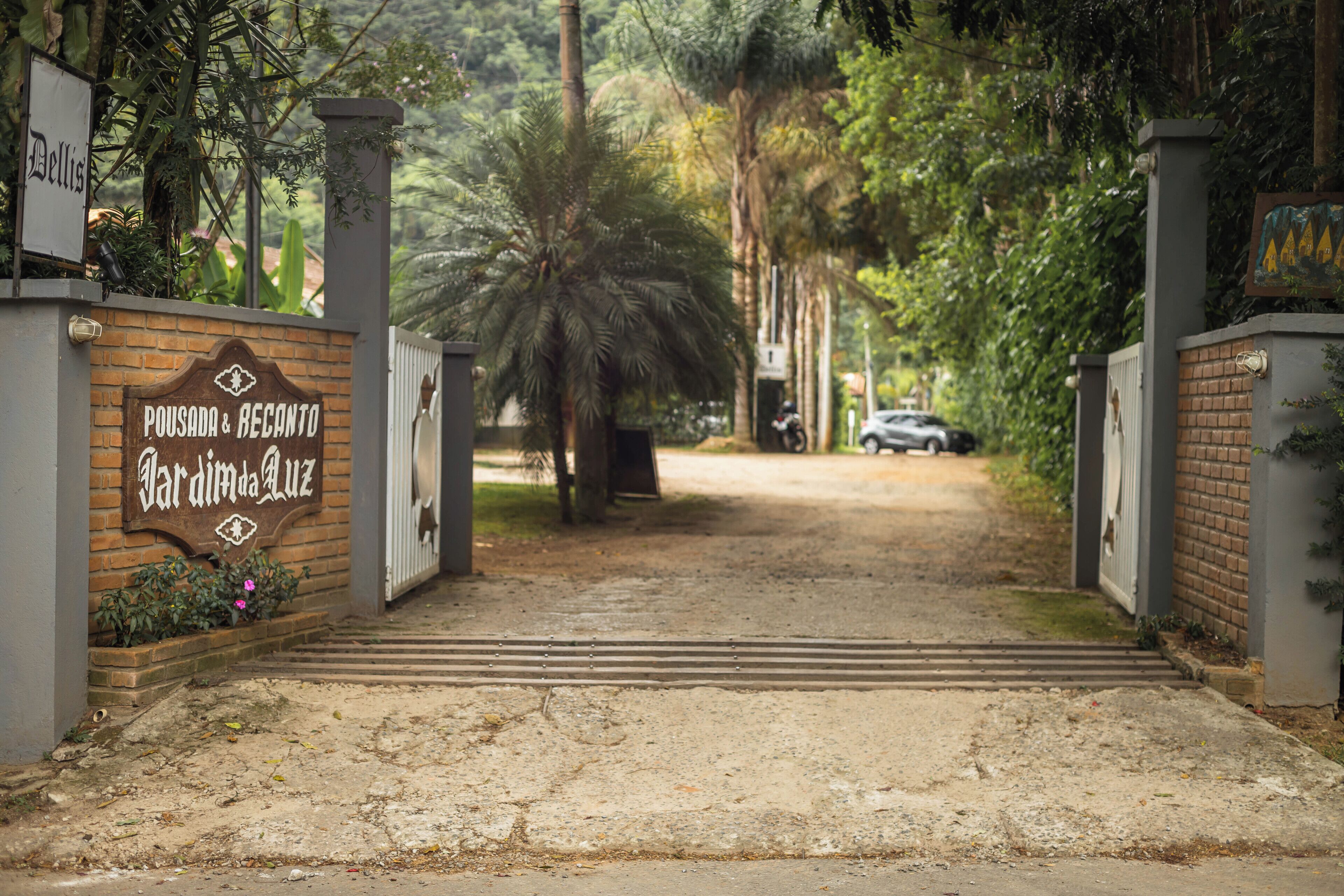 Uma entrada gradeada com uma placa que diz 'Pousada & Recanto Jardim da Luz'.