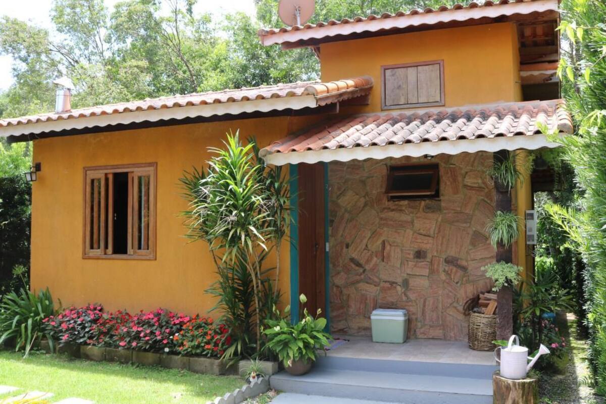 Una casa de dos plantas con fachada amarilla, entrada de piedra y tejado de tejas.