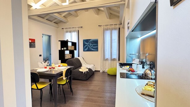 Ein modernes Wohnzimmer mit Essbereich, einer Küche und einem Tisch, der mit Tellern und Besteck gedeckt ist.