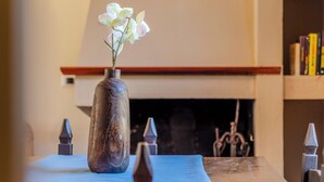 Un comedor con una mesa dispuesta para dos, un florero con flores y una chimenea al fondo.
