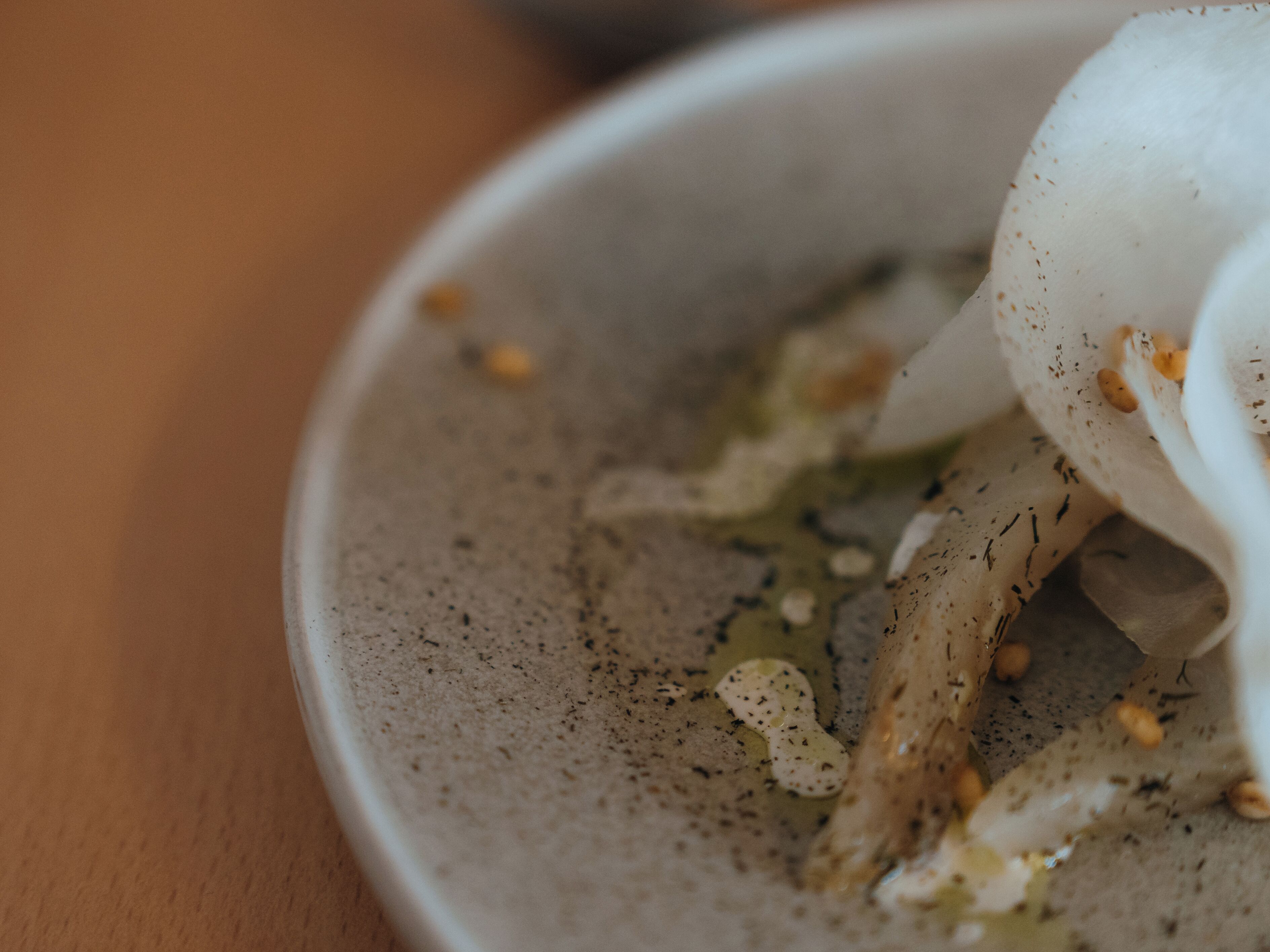 A close-up of a bowl with a creamy substance and some herbs.